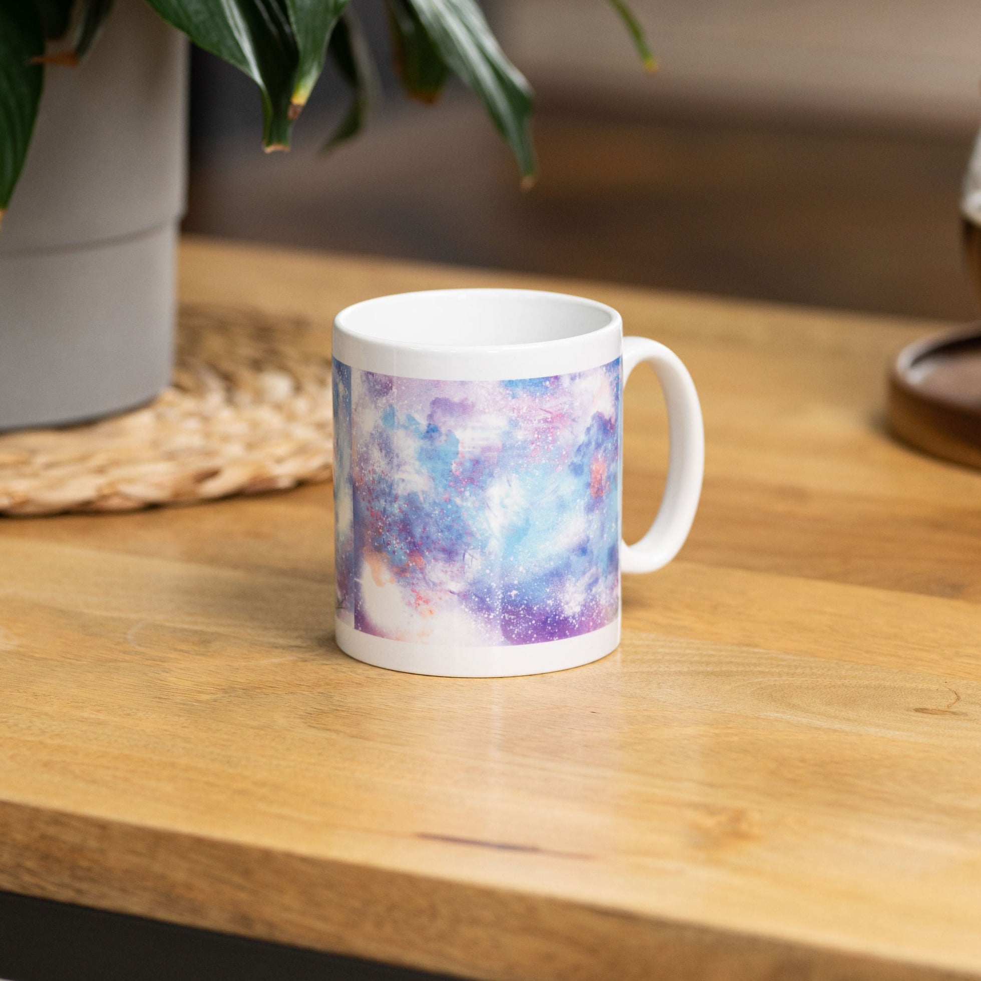 Starry Skies: Digital Pastel Galaxy 11oz Ceramic Mug for Coffee &amp; Tea Lovers |  on a wooden table surrounded by a pot of coffee and a potted plant